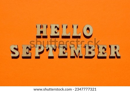 Hello September, words in wooden alphabet letters isolated on orange background as banner headline