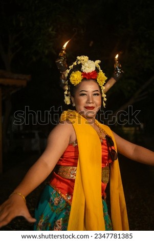 a traditional Javanese dancer dances with colorful flowers on her fist while on stage at night