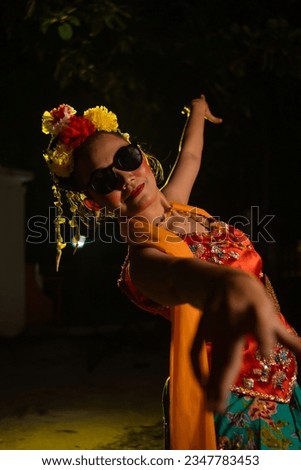 a Sundanese dancer dances very agilely while wearing sunglasses on her face at night