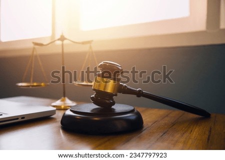 Justice and law concept.Male judge in a courtroom with the gavel, working with, computer and docking keyboard, eyeglasses, on table in morning light Royalty-Free Stock Photo #2347797923