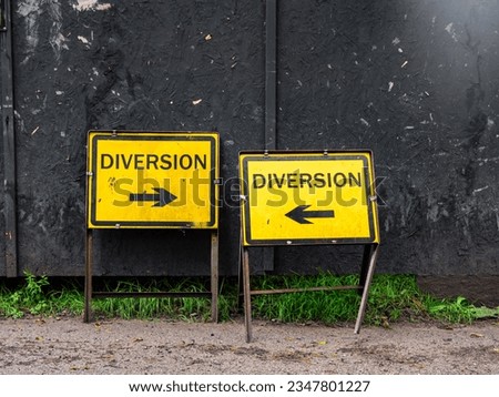 a pair of yellow traffic diversion signs with direction pointing arrows