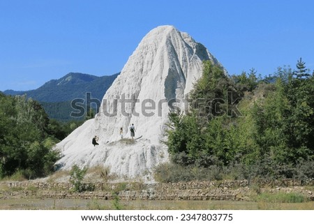 Geological Monument of Romania - White Mound of Grunj.  There are figures of tourists on the rock.