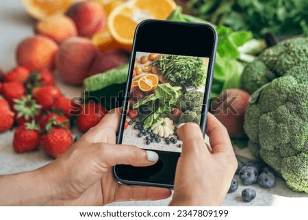 A woman takes a photo of vegetables on a smartphone.