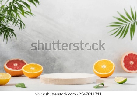 Empty wooden round podium on light grey background surrounded by citrus fruits. Display, pedestal for the presentation of cosmetic products, drinks Royalty-Free Stock Photo #2347811711