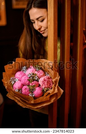 Young beautiful darkhair woman posing with luxury bouquet of fresh pink peonies near wooden doors Royalty-Free Stock Photo #2347814023