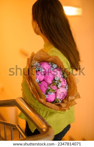Young beautiful darkhair woman in green sweater posing with luxury bouquet of fresh pink peonies in stairwell interior Royalty-Free Stock Photo #2347814071