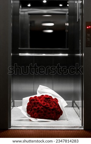 Luxury bouquet of fresh red roses in white wrapping paper on elevator's floor. Flovers delivery. Gift for loved one.