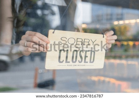 Female store owner turning close sign board of start up coffee shop cafe and restaurant through the door glass and closing the daily service