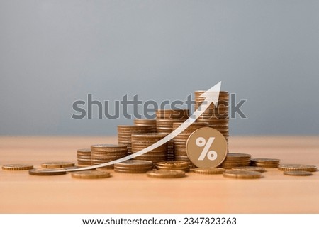 Stack of silver coins with up arrow and percentage symbol on wooden table. Interest rate, financial and dividend concept. return on stocks and mutual funds, long term investment for retirement. 