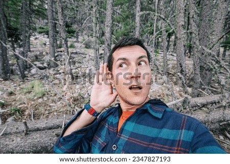 A frightened and lost male hiker heard some rustling in the forest and took it for a wild animal or a bear looks around in the forest. Royalty-Free Stock Photo #2347827193