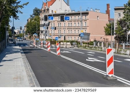 Red and white delineators. Road plates for vertical marking. Road signs within the city - car traffic. New asphalt with white arrows.