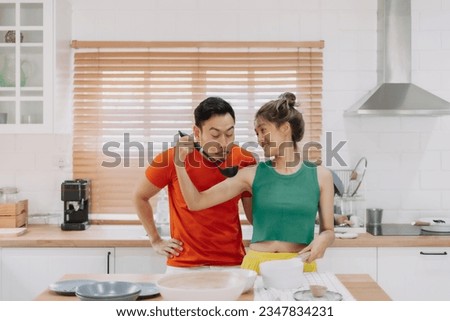 Asian Wife cooking for husband and he tastes the delicious food with smile.