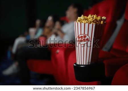 pop corn and happy people in cinema enjoying a movie, popcorns and beverages over the weekend. Royalty-Free Stock Photo #2347856967