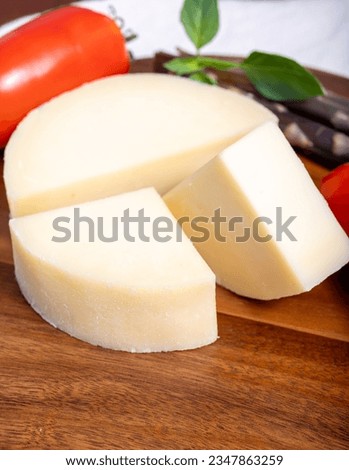 Italian cheese, Provolone dolce cow cheese from Cremona served with olive bread and tomatoes close up. Royalty-Free Stock Photo #2347863259