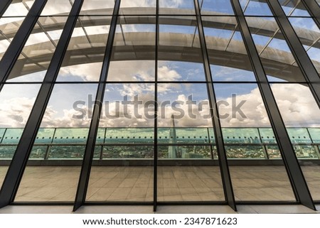 London cityscape with clouds and city buildings, from inside a modern glass skyscraper. The London city aerial skyline panoramic view set in a creative artistic design form, perfect for backgrounds.