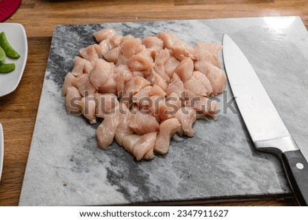 Raw chopped chicken on a marble chopping board with kitchen knife 