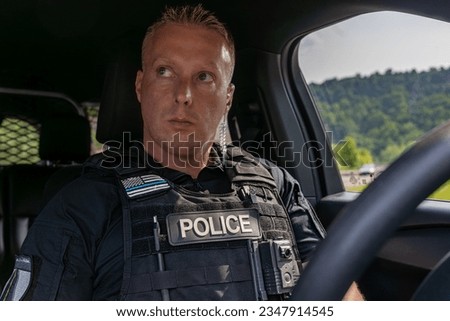 In his cruiser on the interstate, a vigilant cop watches traffic with seasoned eyes, poised to act. The hum of the engine underscores a silent oath to protect and serve. Royalty-Free Stock Photo #2347914545