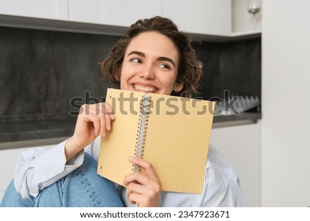 Happy young woman studying at home, reading journal, preparing for exam, looking at her notes in notebook. Copy space