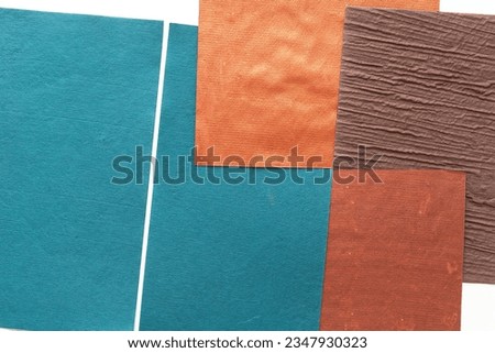 blue, orange-bronze, and textured brown crafting sheets arranged as paper background on white Royalty-Free Stock Photo #2347930323