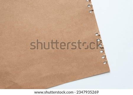 torn coil note book sheet and arranged as a decorative plain brown paper backdrop on white