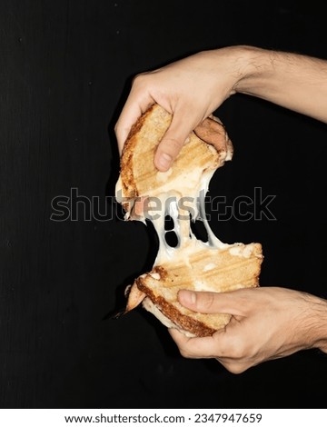 cheese sandwich with ham melted cheese, latino man on black background holding food Royalty-Free Stock Photo #2347947659