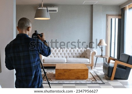 Male professional photographer shooting indoors in the living room, home photography for real estate, selling houses and apartments, including interior design Royalty-Free Stock Photo #2347956627