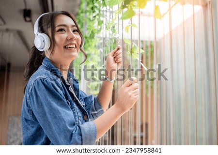 Happy woman wearing jean shirt on holiday at coffee corner listening music from Bluetooth earphone  is business relaxing concept. Royalty-Free Stock Photo #2347958841
