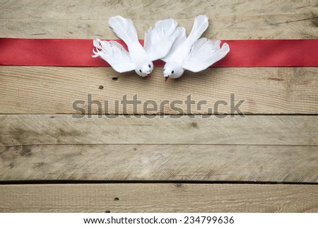 White peace doves on red ribbon and wooden background