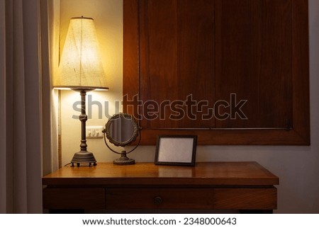 vintage table lamp and mirror with picture frame on wooden desk in the bedroom at night time