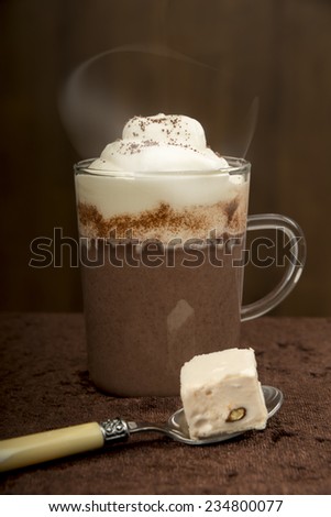 Hot chocolate with cream, spoon with almond nougat