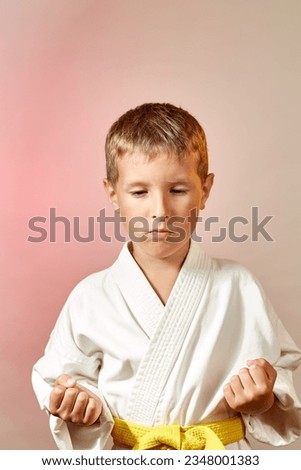 On a gradient colored background, a focused child in karategi Royalty-Free Stock Photo #2348001383
