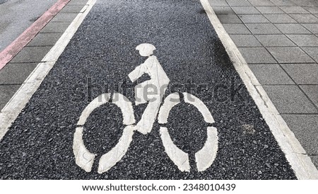 A cyclist sign on the road surface in the bike lane.