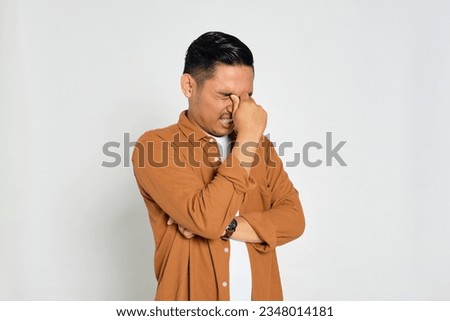 Portrait of tired young Asian man in casual shirt rubbing eyes with finger isolated on white background Royalty-Free Stock Photo #2348014181