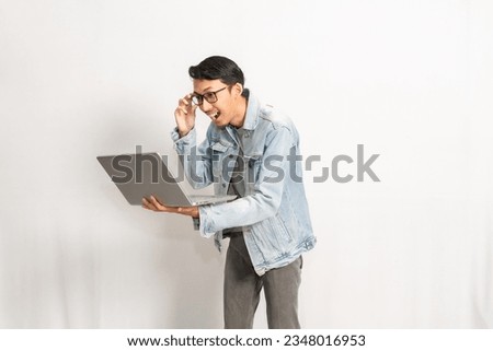 A man shock while looking at his laptop. Indonesian or southeast asian model isolated with white wall background. Royalty-Free Stock Photo #2348016953
