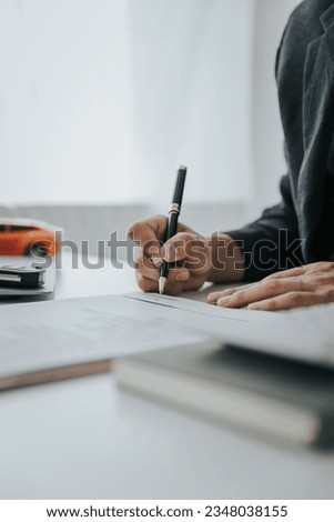 Closing sale. Asian customer signing car insurance paperwork or lease contract or agreement. Buy or sell a new or used car with car keys on the table.	