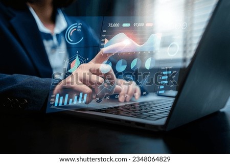 Businesswoman analyzes to chart data business on a visual screen dashboard, technology devices and screens visible in the background, financial planning, market research, and the stock market. Royalty-Free Stock Photo #2348064829