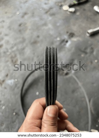 A car fan belt that is starting to get brittle due to age was photographed at a repair shop.