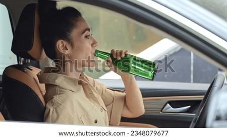 Drunk businesswoman drives car holding green bottle of alcohol in hand. Businesswoman driver neglects health and wellbeing disobeying traffic rules Royalty-Free Stock Photo #2348079677