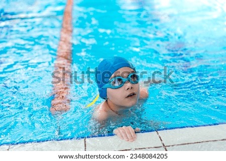 little caucasian boy wearing goggles looking out from swimming pool. High quality photo with selective focus