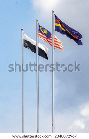 Malaysia flag and Pahang flag blowing in the wind in front of a clear blue sky