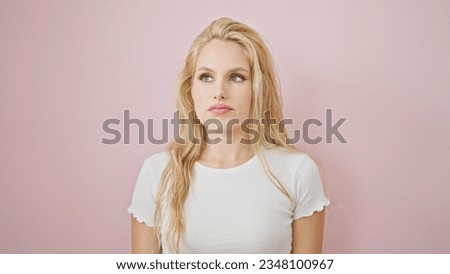 Young blonde woman standing with serious expression over isolated pink background