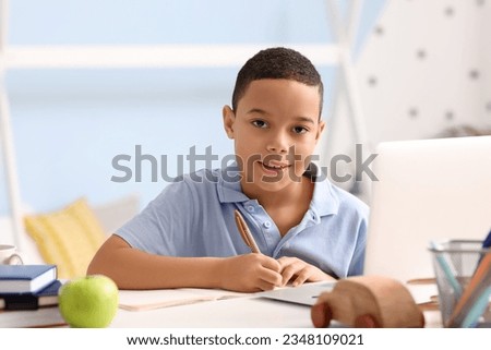 Little African-American boy studying computer sciences online in bedroom Royalty-Free Stock Photo #2348109021