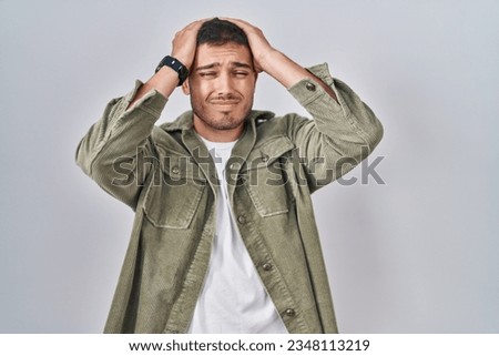 Young hispanic man standing over isolated background suffering from headache desperate and stressed because pain and migraine. hands on head.  Royalty-Free Stock Photo #2348113219