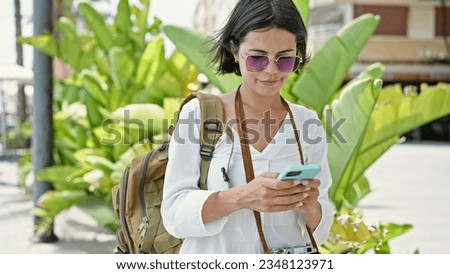 Young beautiful hispanic woman tourist using smartphone at park