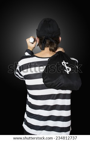 Burglar with flashlight, hat and money bag on black background.