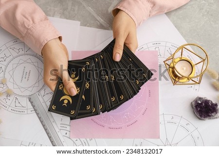 Woman using tarot cards at table, top view. Astrological predictions