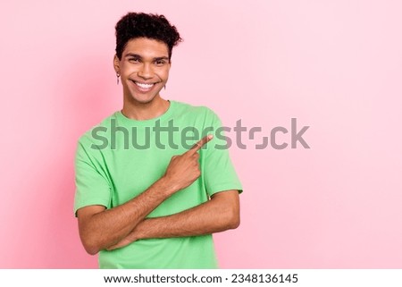 Photo of confident cheerful guy wear green t-shirt pointing finger empty space isolated pink color background