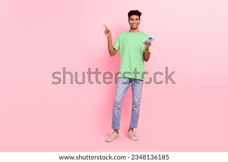 Full length photo of good mood man dressed stylish t-shirt hold smartphone indicating empty space offer isolated on pink color background