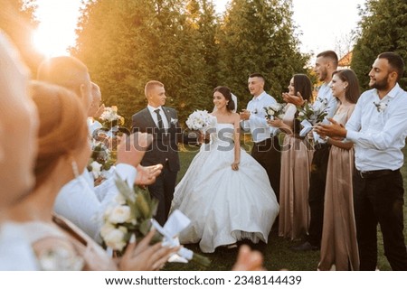 Wide angle shot of bride and groom walking down the aisle after their wedding ceremony at sunset as friends and family celebrate Royalty-Free Stock Photo #2348144439