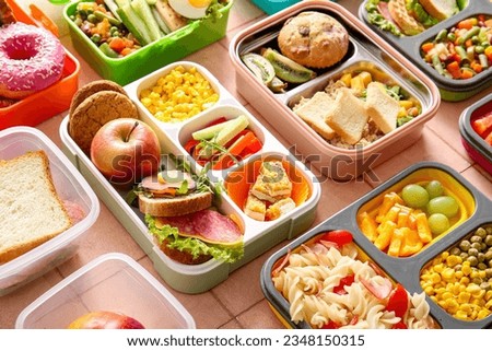 Many lunchboxes with different delicious food on pink tile background Royalty-Free Stock Photo #2348150315